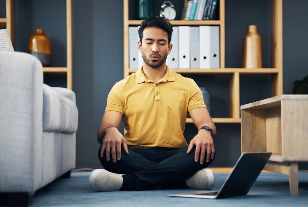 Méditation, ordinateur portable et un homme faisant du yoga pour la santé mentale, le bien-être ou le zen sur le sol de sa maison, après avoir calculé son reste à vivre pour un achat immobilier. 